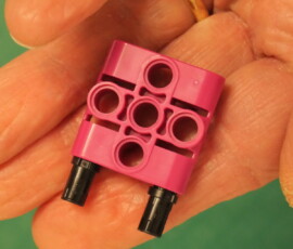 Center hole to support axle. Mounts to frame with two black pins.